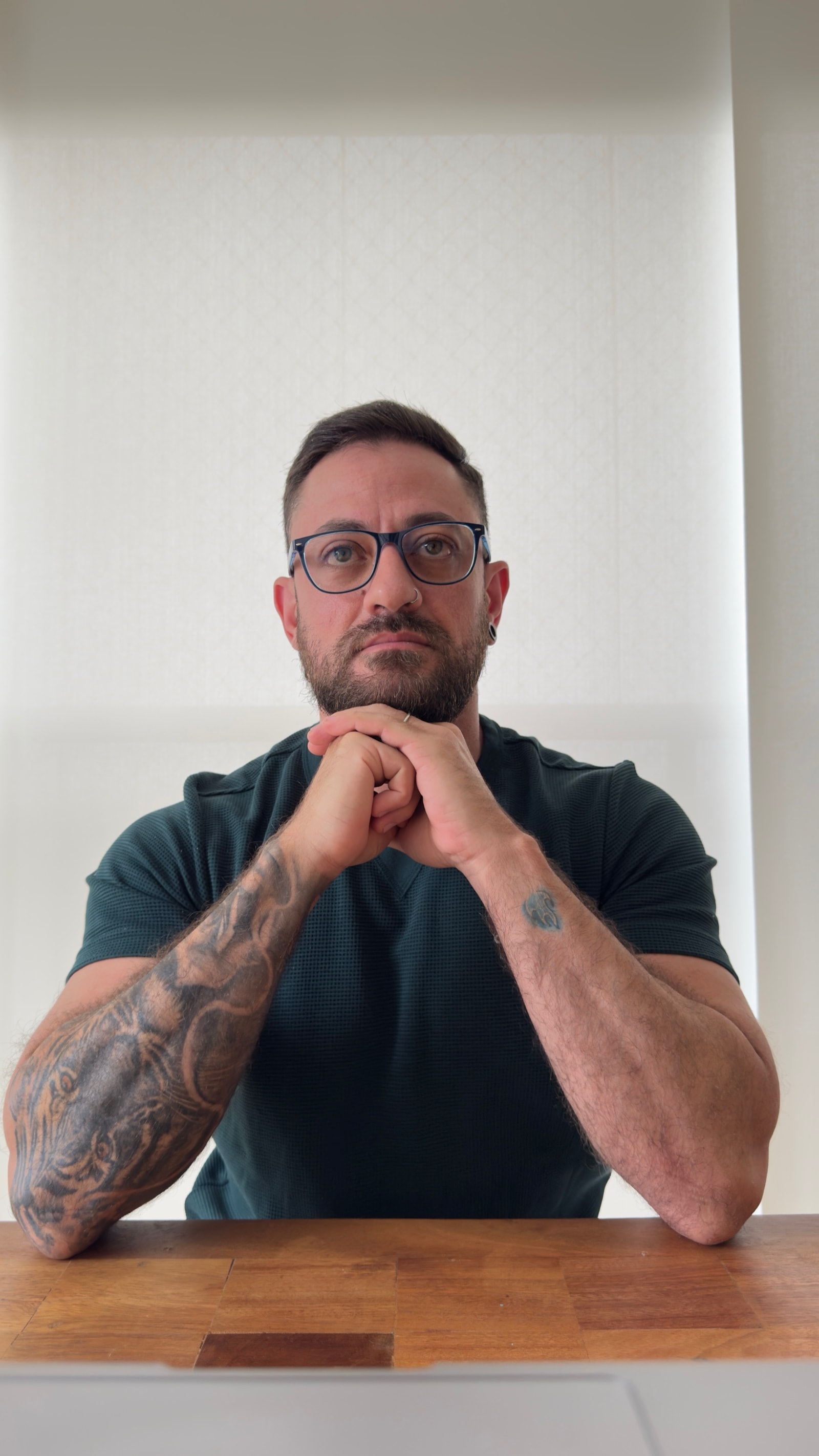 Caio César, psicanalista clínico, sentado à mesa com as mãos unidas sob o queixo, olhando para a câmera